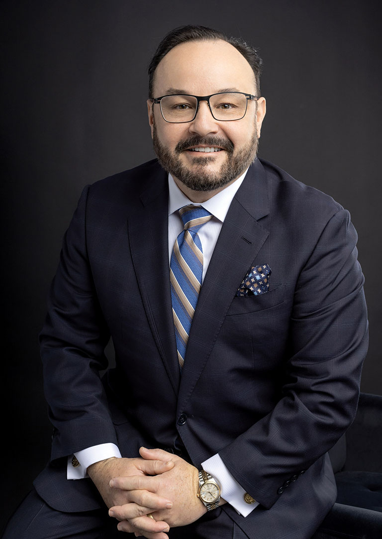 Dr. Aldo Guerra wearing suit with a striped tie
